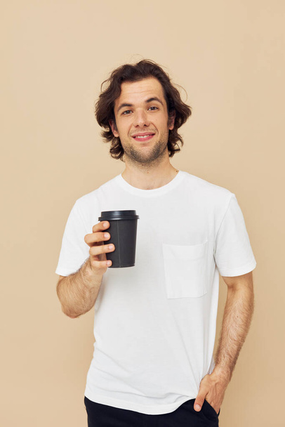handsome man in a white T-shirt with a black glass in hand Lifestyle unaltered - Zdjęcie, obraz