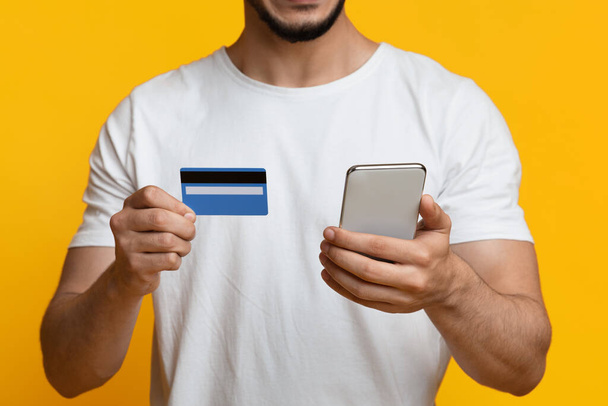 Обрізаний середній східний хлопець зі смартфоном і кредитною карткою
 - Фото, зображення