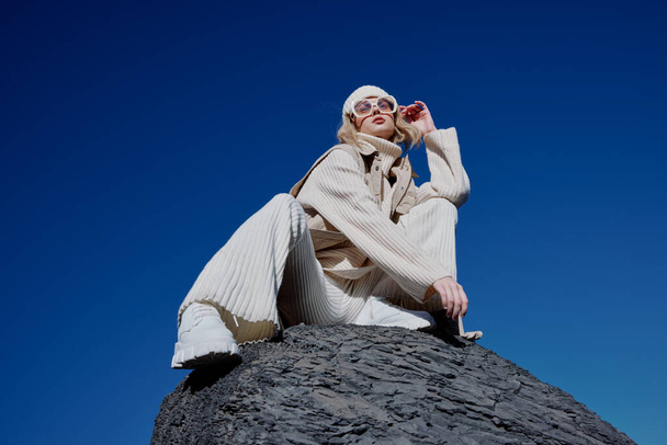 Sonbahar elbiseli bir kadın bir kayanın üzerinde duruyor. Mavi gökyüzü manzarası. - Fotoğraf, Görsel