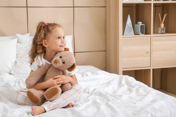 Yatak odasında oyuncak ayıyla sevimli küçük bir kız - Fotoğraf, Görsel