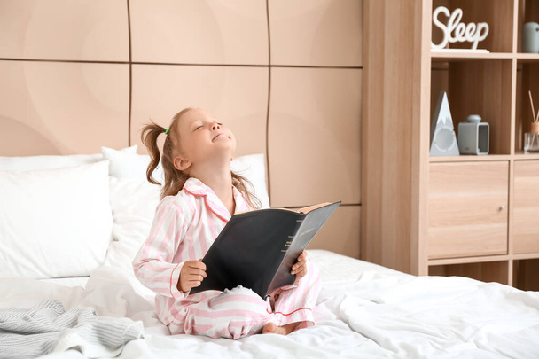 Imádnivaló kislány Szent Bibliával a hálószobában - Fotó, kép