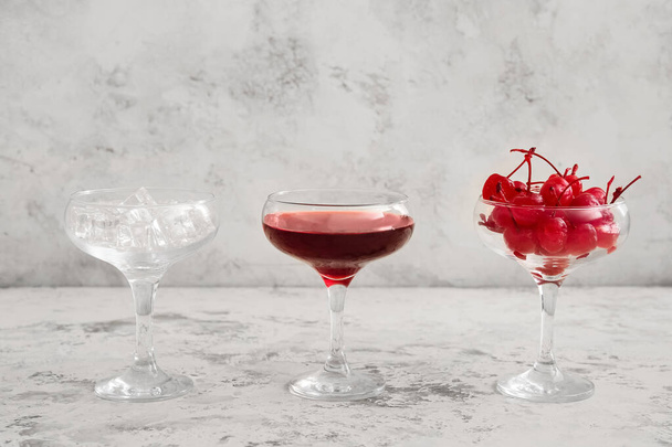 Glass of tasty Manhattan cocktail with ice and cherries on light background - Foto, imagen