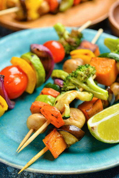 Тарілка зі смачними овочевими шампурами і лаймом на столі, крупним планом
 - Фото, зображення