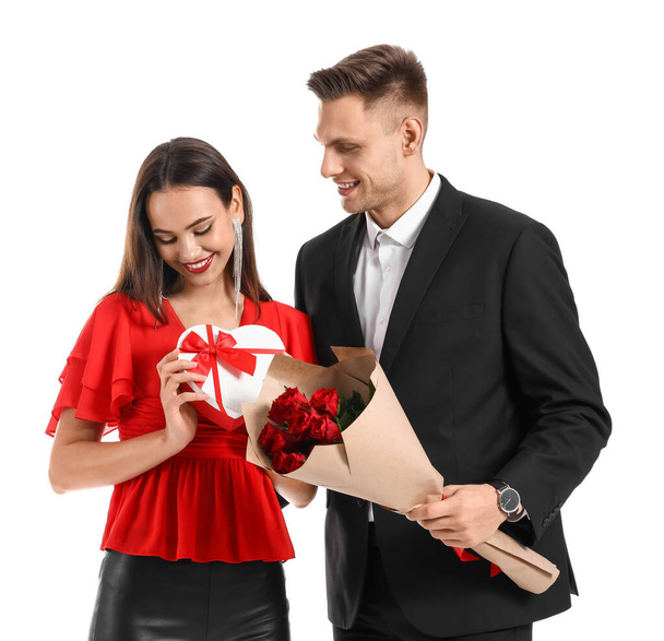 Happy young couple with gift and bouquet of flowers on white background. Valentine's Day celebration - Fotoğraf, Görsel