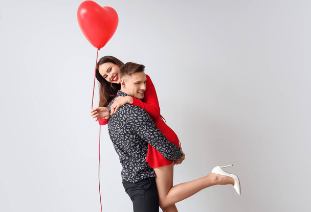 Szczęśliwa młoda para z balonem na jasnym tle. Święto Walentynek - Zdjęcie, obraz