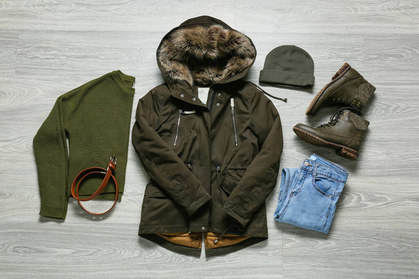 Chaqueta, pantalones, suéter, sombrero, zapatos y cinturón sobre fondo de madera gris - Foto, Imagen