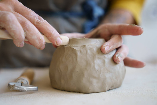 Ceramics creation process: female artist shaping and sculpting clay pottery. Working table in studio - Φωτογραφία, εικόνα