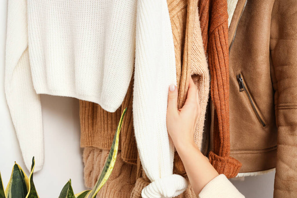 Mulher com camisolas de malha penduradas em guarda-roupa, close-up - Foto, Imagem
