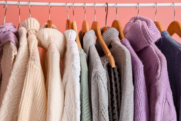 Rack with stylish warm sweaters near pink wall, closeup - Foto, imagen