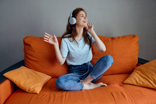 усміхнена жінка навушники вдома на дивані розваги незмінні
 - Фото, зображення