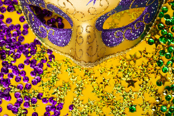 Mardi Gras contas de cor de ouro com máscaras de luxo venetian festival máscara de carnaval e dourado, verde, confete roxo no fundo amarelo. Convite do partido, cartão de saudação, conceito venetian carnivale celebração. - Foto, Imagem