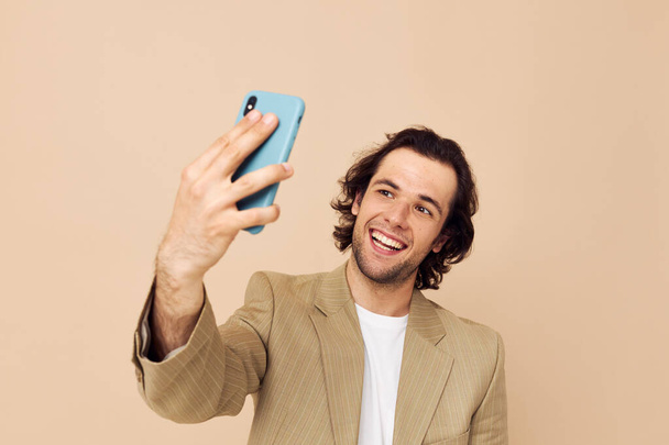handsome man with a phone in hand beige suit elegant style Lifestyle unaltered - Foto, Imagen
