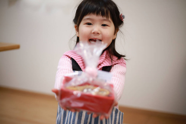 可愛いアジア系の女の子がクッキーを持って - 写真・画像