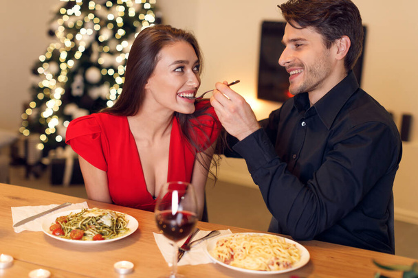 Handsome guy feeding his woman with pasta - 写真・画像