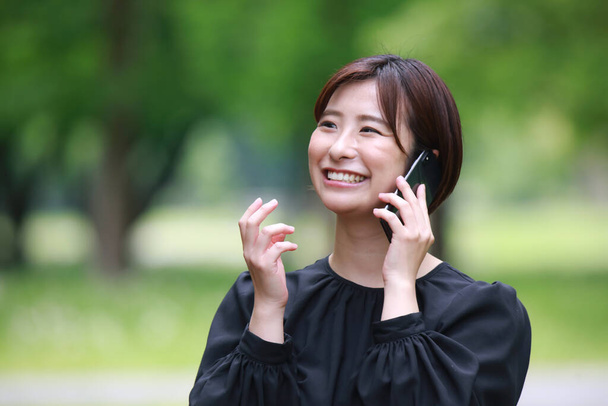 jovem asiático mulher chamada no o celular no o parque - Foto, Imagem