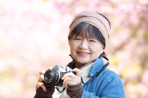 Egy idősebb nő képe, amint fotózkodik. - Fotó, kép