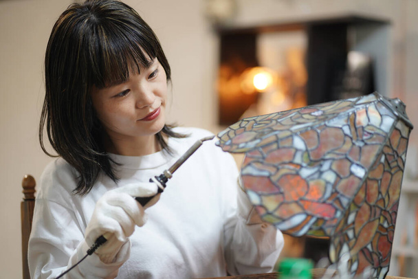 Nuori aasialainen nainen käyttää juotin luoda kaunis koristelu - Valokuva, kuva