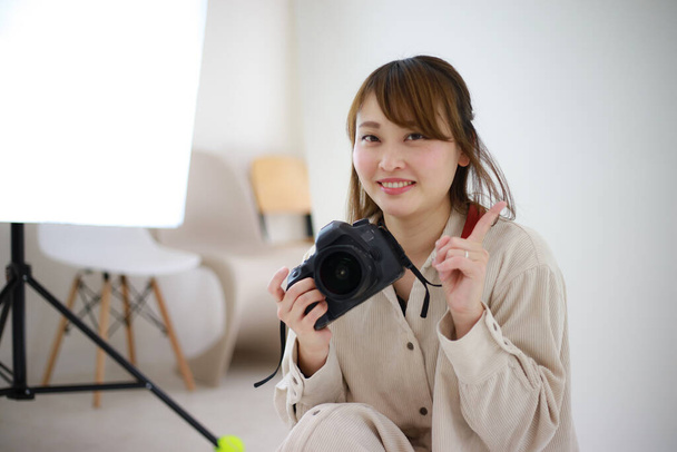 beautiful young woman photographer with camera in studio  - Foto, imagen