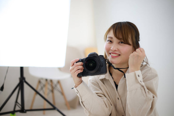 beautiful young woman photographer with camera in studio  - Фото, изображение