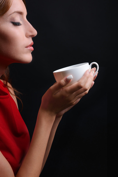 Beautiful young girl with cup of coffee on black background - Zdjęcie, obraz