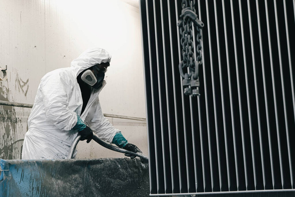 Εργοστάσιο, προσωπικό φορούν χημικά προστατευτικά ρούχα στη δουλειά. Ψεκασμός χρωμάτων. - Φωτογραφία, εικόνα
