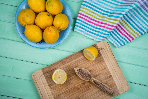 Органические лимоны и соковыжималка на столе
 - Фото, изображение