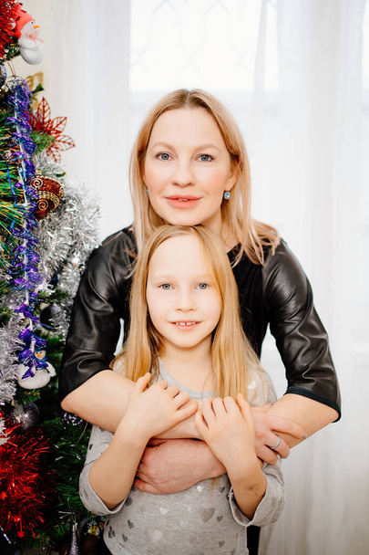 portrait of blonde mom and little girl at the Christmas tree. - Fotó, kép