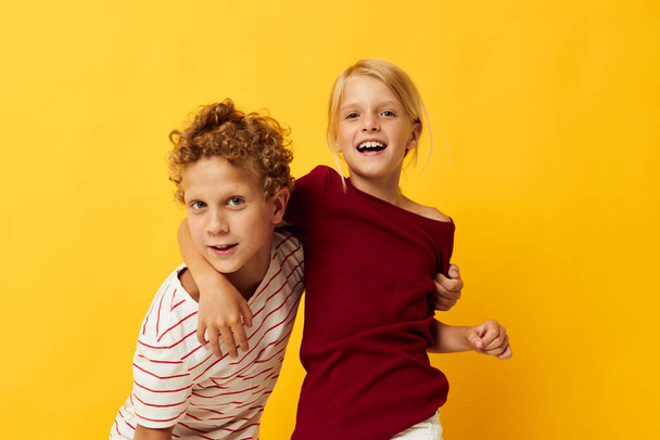 Boy and girl standing side by side posing childhood emotions on colored background - Foto, immagini