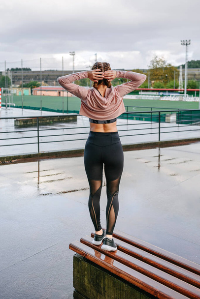 Young sportswoman stretching neck and shoulders outdoors - Photo, image