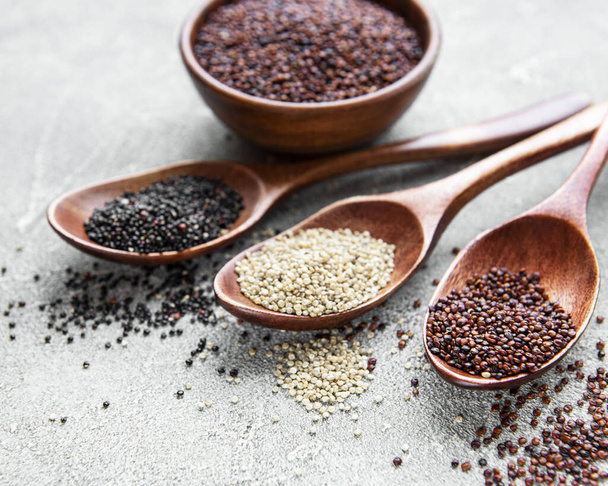 Punaiset, mustat ja valkoiset kvinoan siemenet konkreettisella pohjalla - Valokuva, kuva