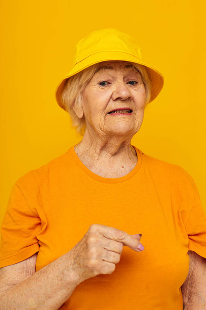 femme âgée en t-shirt décontracté panama jaune fond isolé - Photo, image