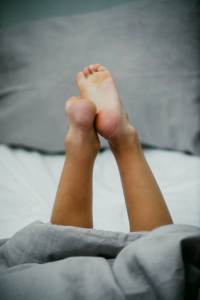 piccoli piedi bambino su biancheria da letto leggera primo piano - Foto, immagini