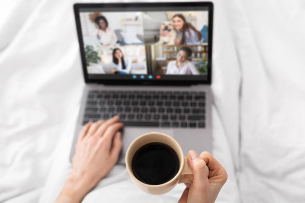 Virtuele ontmoeting. Onherkenbare dame drinken koffie en het maken van video gesprek met vrienden - Foto, afbeelding