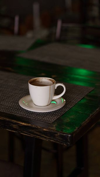 a mug of coffee stands on a tray in a restaurant.  dark colors, loft style interior.  no people - 写真・画像