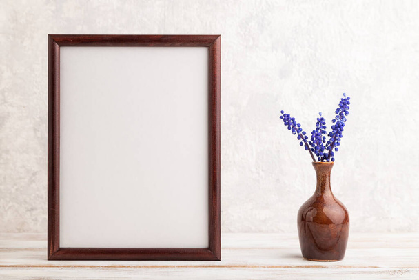 Wooden frame with blue muscari hyacinth flowers in ceramic vase on gray concrete background. side view, copy space, still life, mockup, template, spring, summer minimalism concept. - Photo, Image