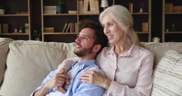 Dreamy adult son his older mom daydreaming relax on sofa - Imágenes, Vídeo