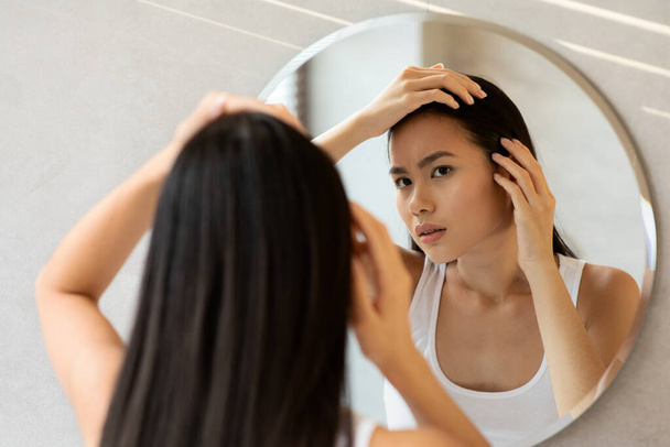 Verärgert langhaarige Japanerin überprüft ihr Haar - Foto, Bild