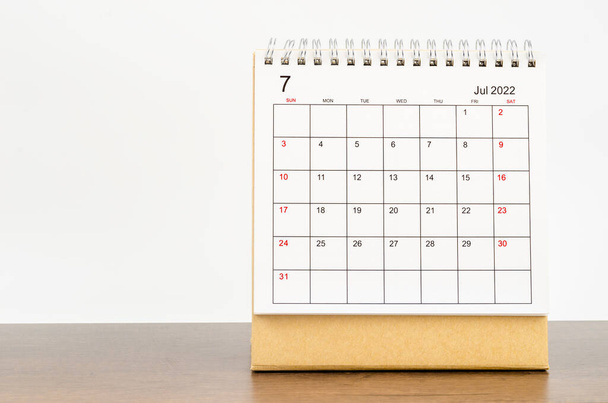 The July 2022 desk calendar on wooden table. - Φωτογραφία, εικόνα