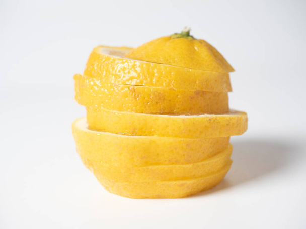Крупный план лимона, разрезанного на ломтики на белом фоне. изолированные фрукты. Кислый желтый фрукт, полный витаминов. - Фото, изображение