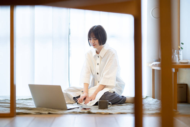 Жінка дивиться на ноутбук у невимушеній атмосфері у своїй кімнаті
 - Фото, зображення