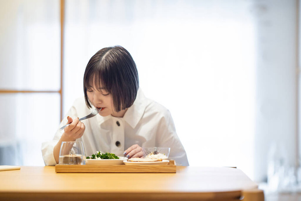 Nuori nainen syö aamiaista huoneessa - Valokuva, kuva