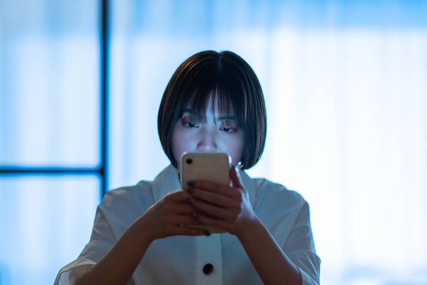 A woman staring at a smartphone with a stern look in the room - Photo, image