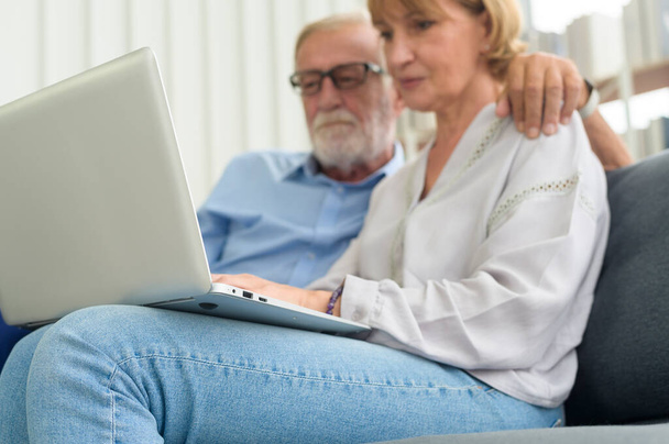 Happy Caucasian senior couple using laptop at home - 写真・画像
