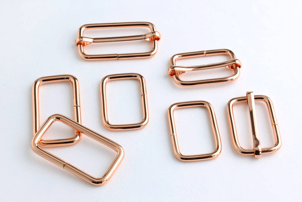 Belt adjuster frames, color red gold. Metal frame with a movable part for changing the length of the strap on the bag. Accessories for sewing backpacks and bags.  - Photo, Image