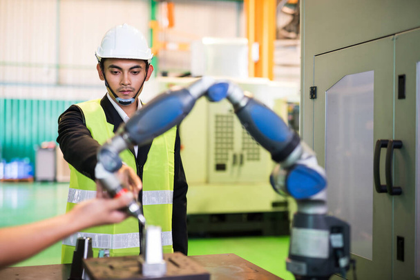 Manažer továrního inženýra ukazuje prstem na objednávku pracovníka, aby nastavil pozici CNC automatického soustružnického robota na ruční frézování náhradních dílů. Výrobní průmysl s vyspělou technologií. - Fotografie, Obrázek