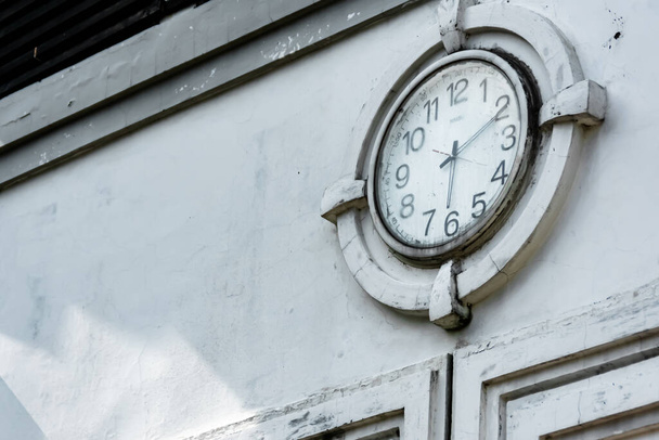 Close-up vintage and retro public city clock showing the time on the white wall ornament - 写真・画像