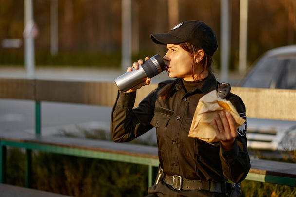 Police woman take break eating in park - Фото, изображение