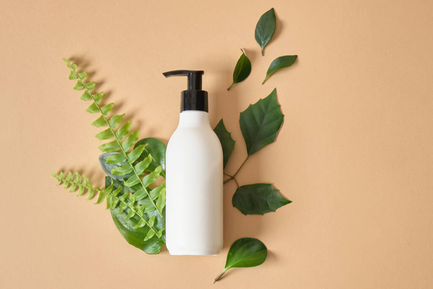 mock up organic cosmetic plastic bottle with dispenser and green leaves. - Fotografie, Obrázek