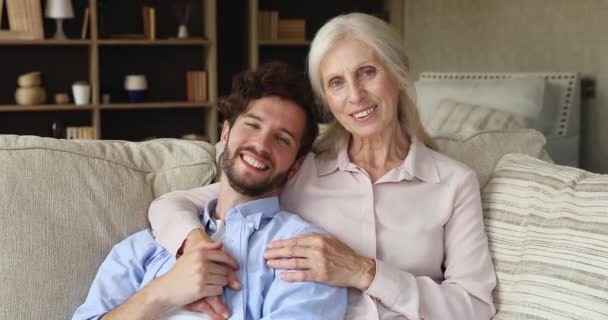 Older mum adult son relax on sofa look at camera - Video