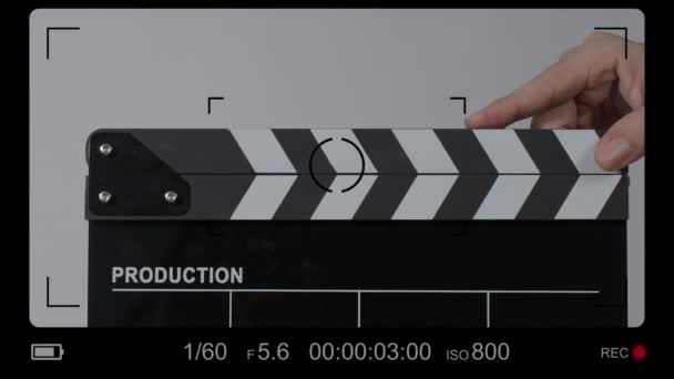 Movie slate or clapperboard hitting. Close up hand holding empty film slate and clapping it. Open and close film slate for video production. film production. color background studio. ready to shoot - Felvétel, videó